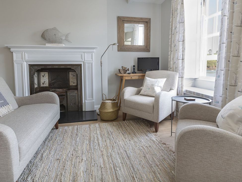 A living room with a fireplace and armchairs at Primrose Cottage Salcombe