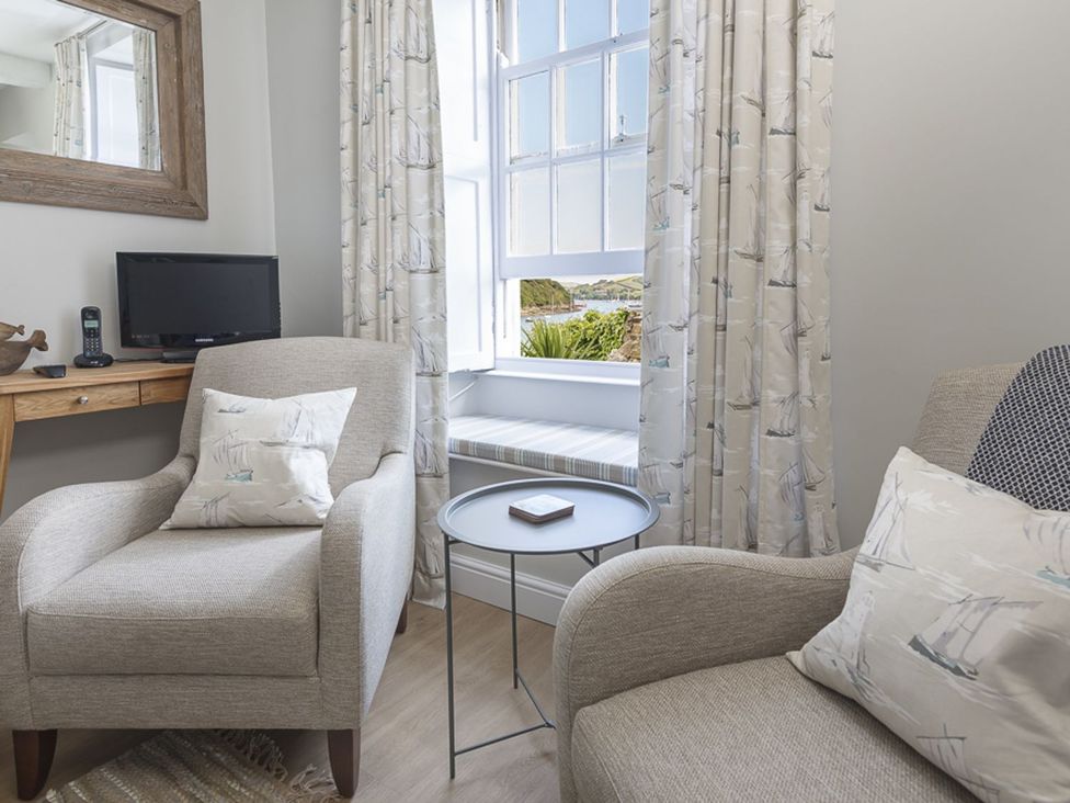 A living room with an armchair and television at Primrose Cottage Salcombe