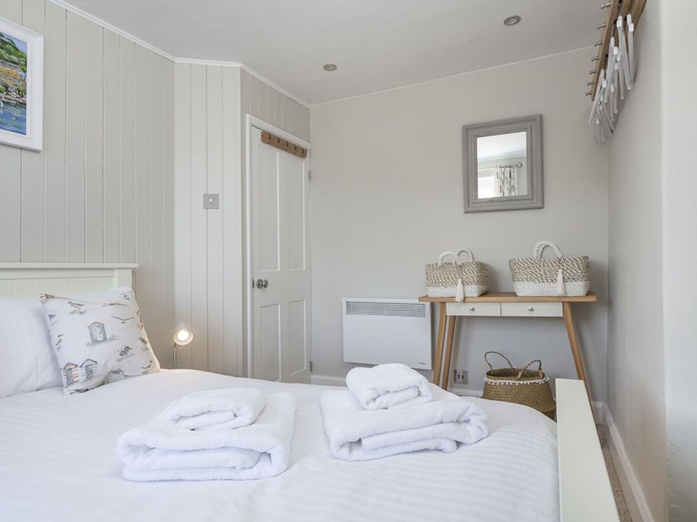 A bedroom with a bed and a table at Primrose Cottage, Salcombe