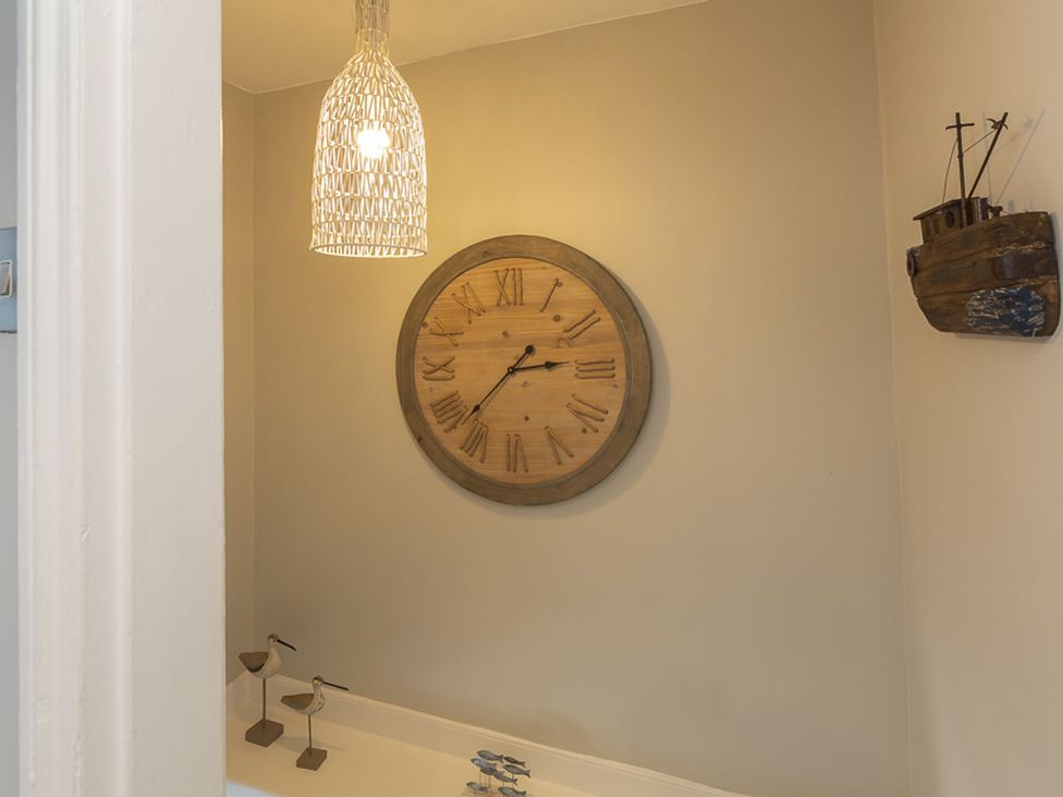 A bathroom with a wooden clock and pendant light at Primrose Cottage in Salcombe