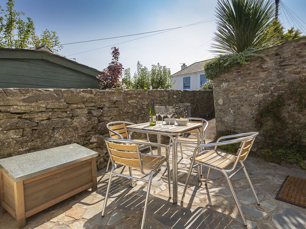 A table with chairs and glasses in an outdoor dining area at Primrose Cottage in Salcombe