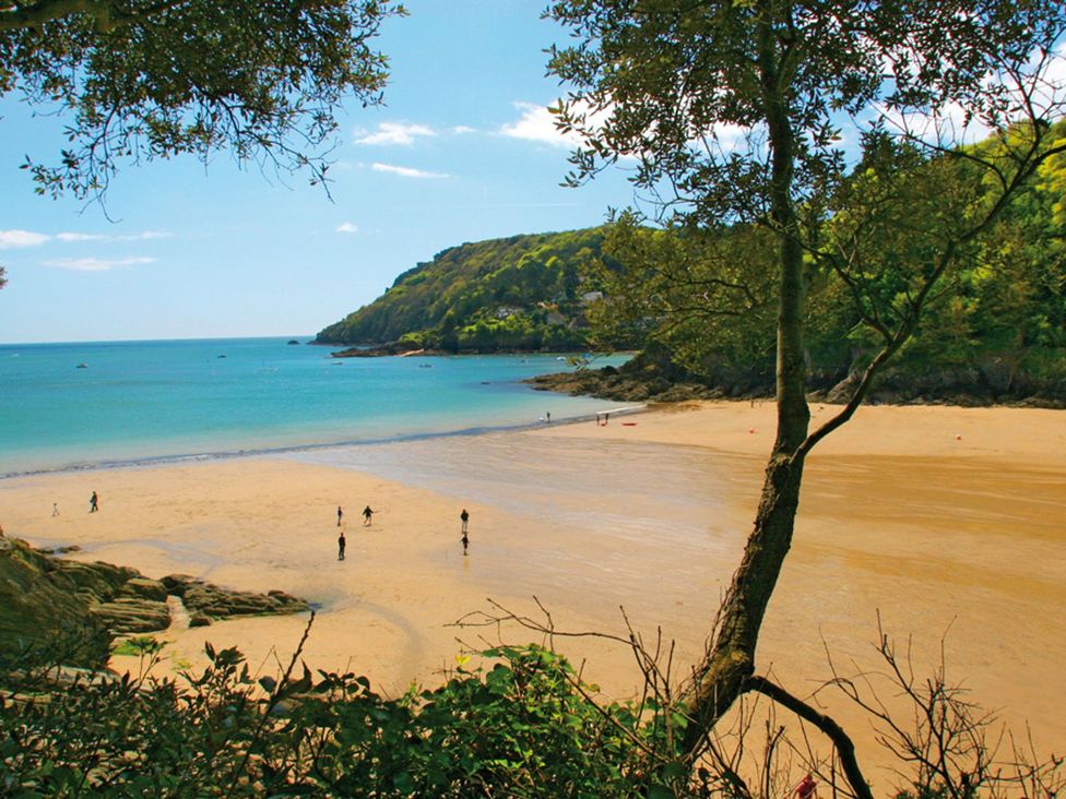 A beach with people walking on the sand near the ocean at Primrose Cottage in Salcombe