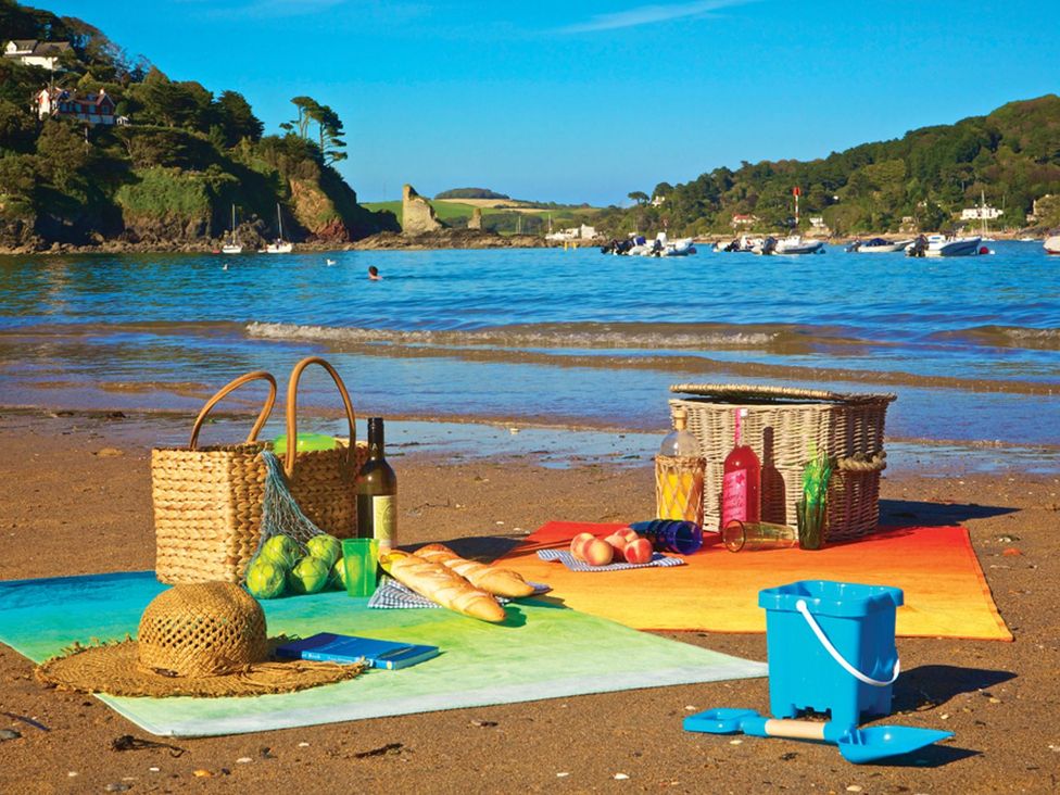 A picnic setup with food and a beach view at Primrose Cottage Salcombe