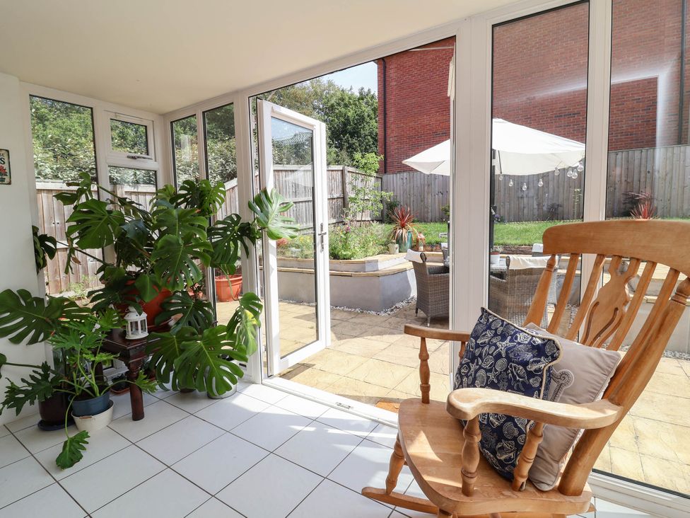 A conservatory with a rocking chair and plants at Manning's View in Barnstaple