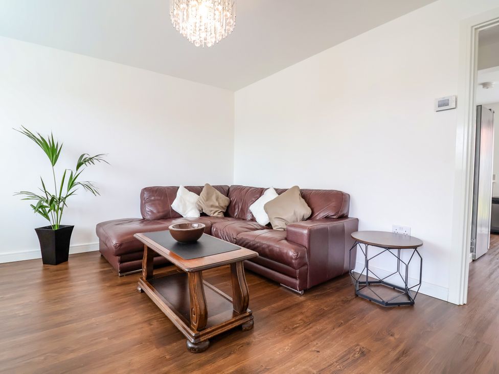 A living room with a sofa, coffee table, and floor plant at 12 Corbetts Close in Crewe
