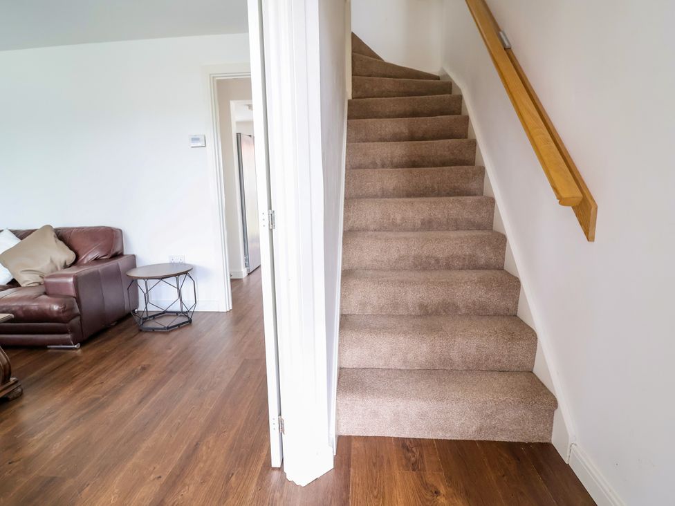 A living room with a staircase and furniture at 12 Corbetts Close Crewe
