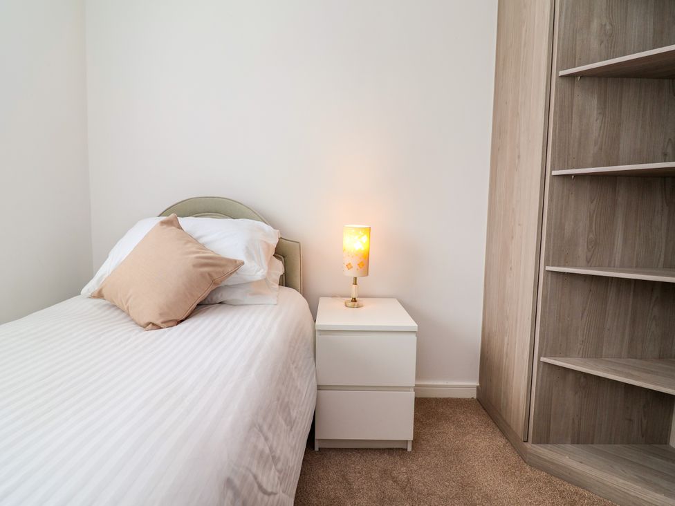 A bedroom with a bed and a lamp on a nightstand at 12 Corbetts Close in Crewe