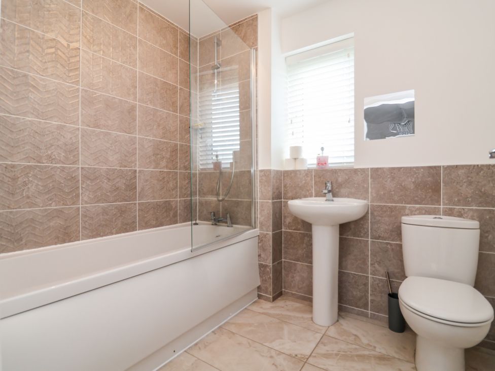 A bathroom with a bathtub, shower, toilet, and sink at 12 Corbetts Close in Crewe