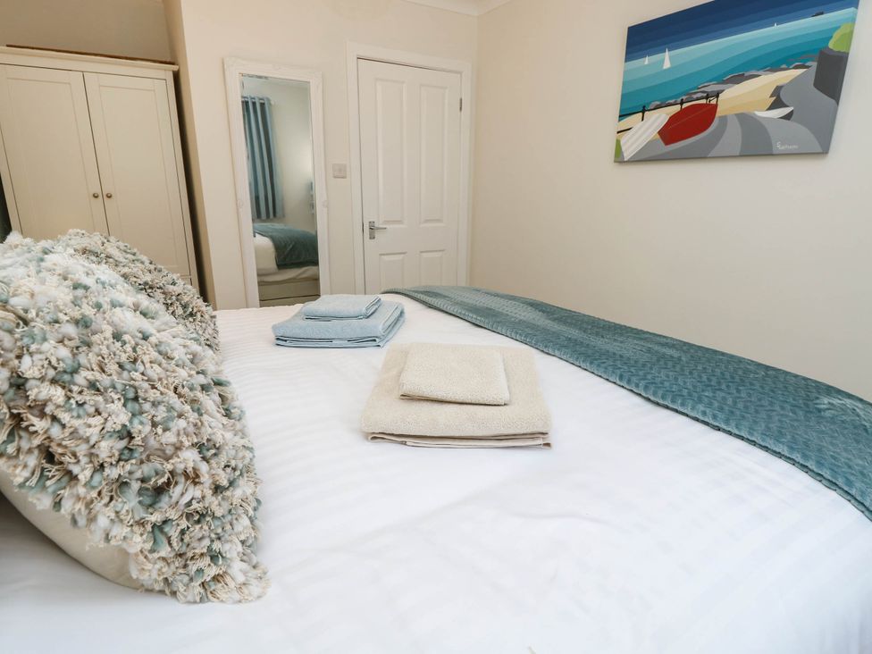 A bedroom with towels neatly arranged on a bed at The Old Post Office in St. Lawrence near Ventnor