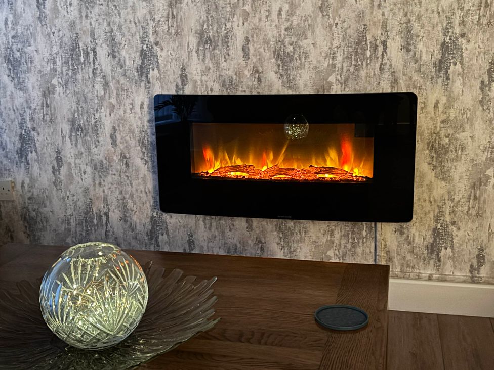 An electric fireplace and decorative vase on a table at The Old Post Office St. Lawrence near Ventnor