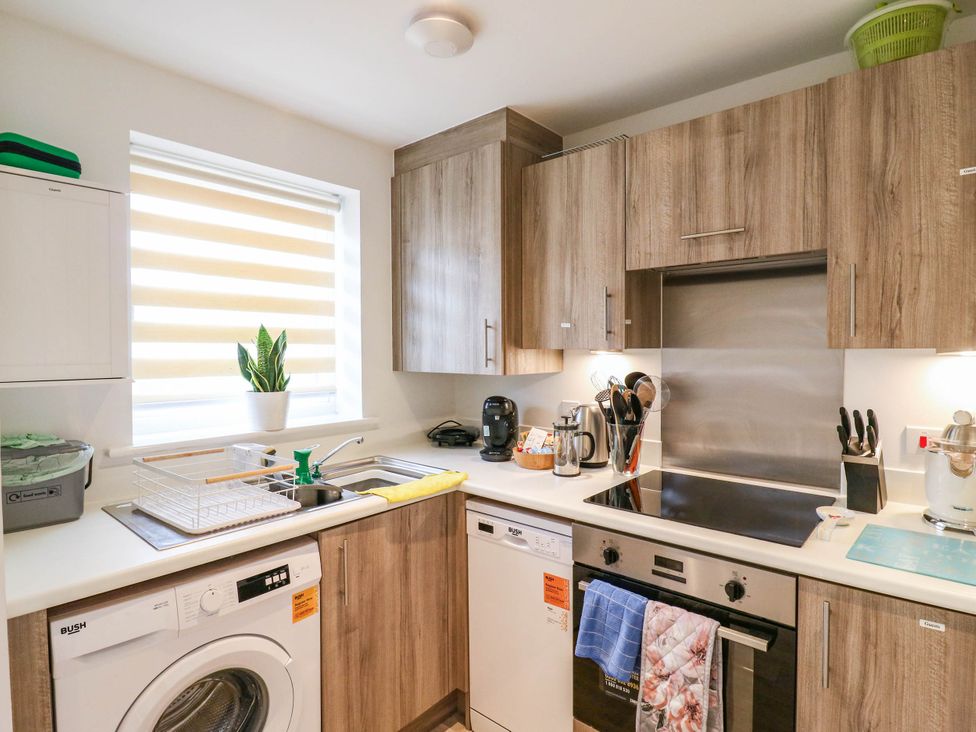 A kitchen with a sink, washing machine, and stove at Serenity House