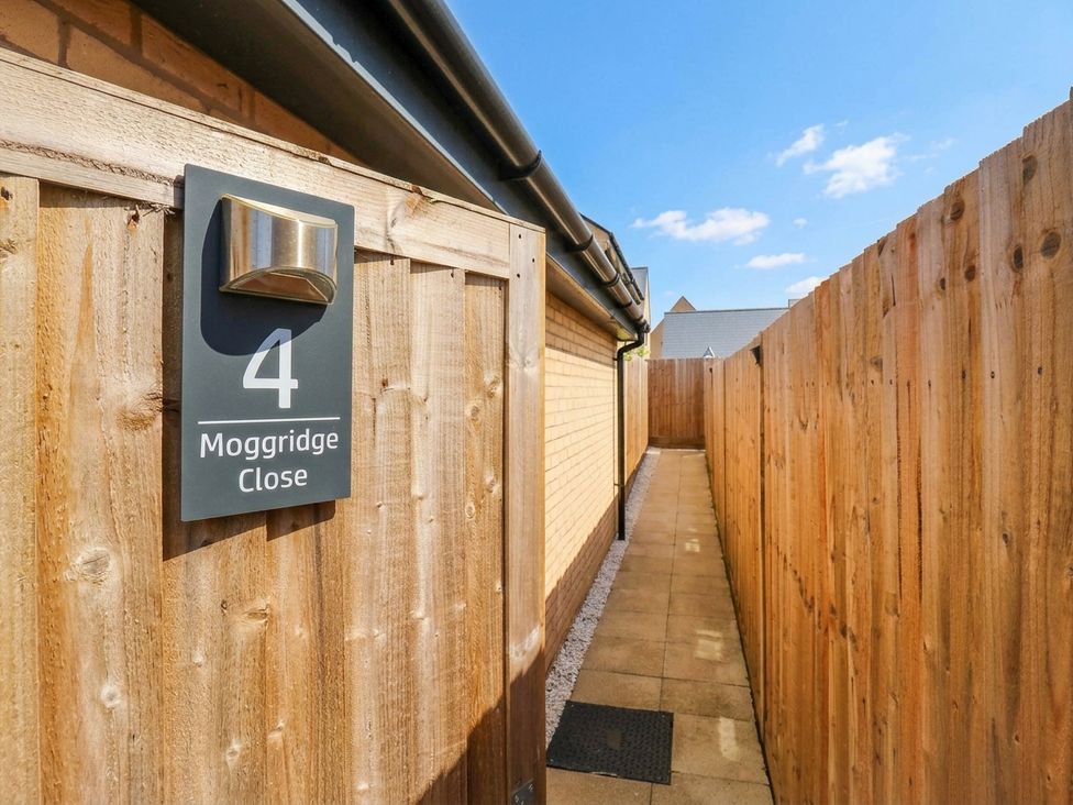 A pathway beside a fence with a house number sign at Serenity House