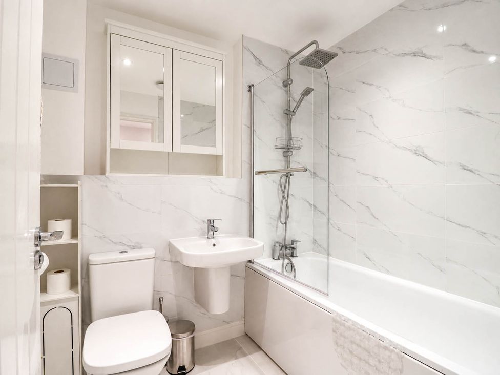A bathroom with a bathtub, toilet, sink, and shower at Serenity House