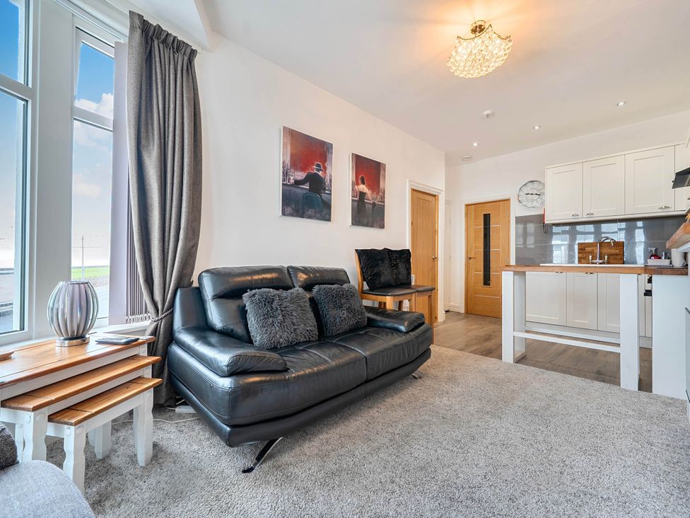 A living room with a sofa and kitchen area at The Old Barn in Bispham