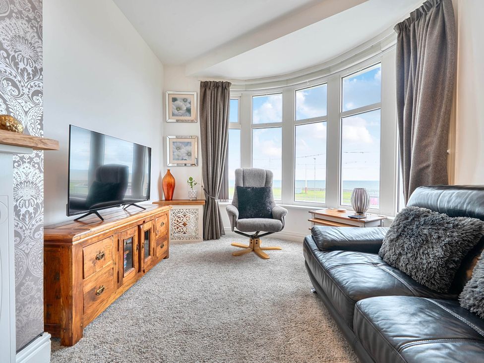 A living room with a television, sofa, and armchair at The Old Barn in Bispham