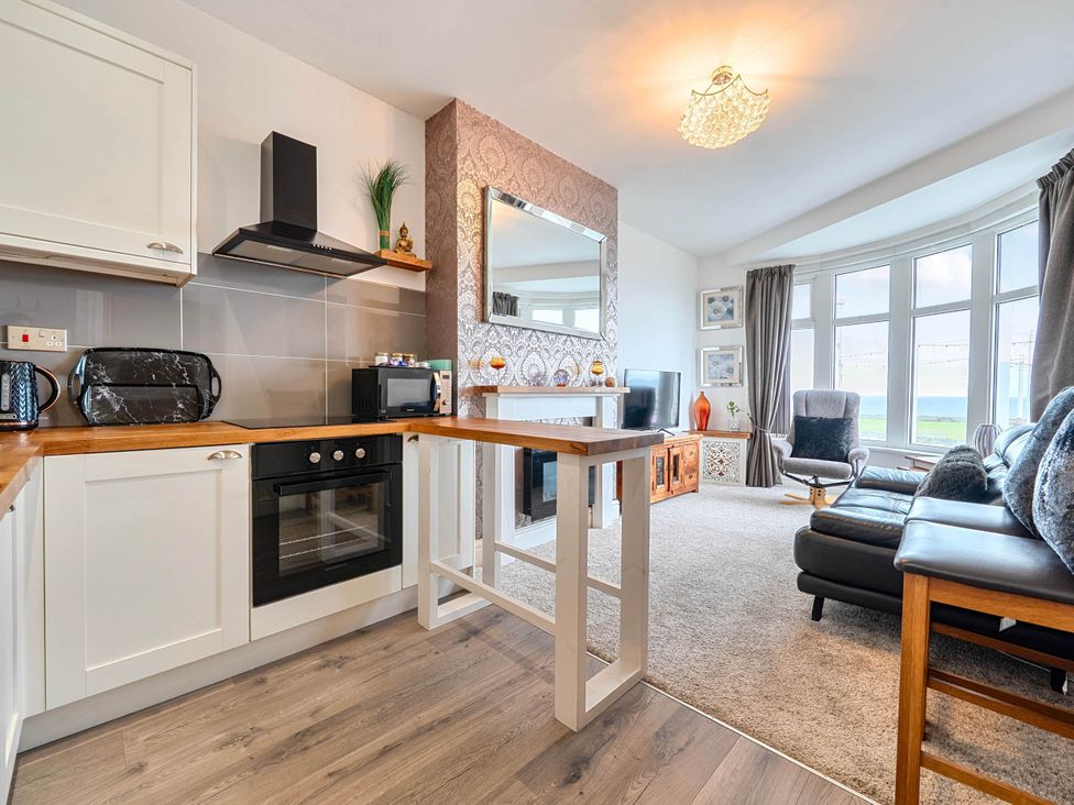 A kitchen with a living area featuring a sofa and television at The Old Barn in Bispham