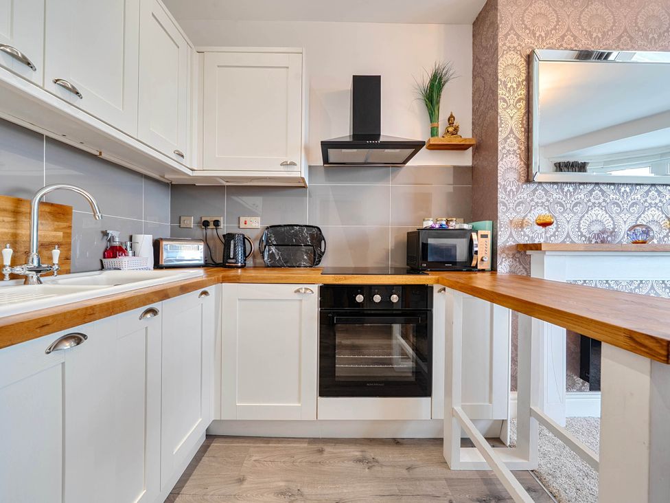 A kitchen with cabinets, sink, oven, and microwave at The Old Barn in Bispham