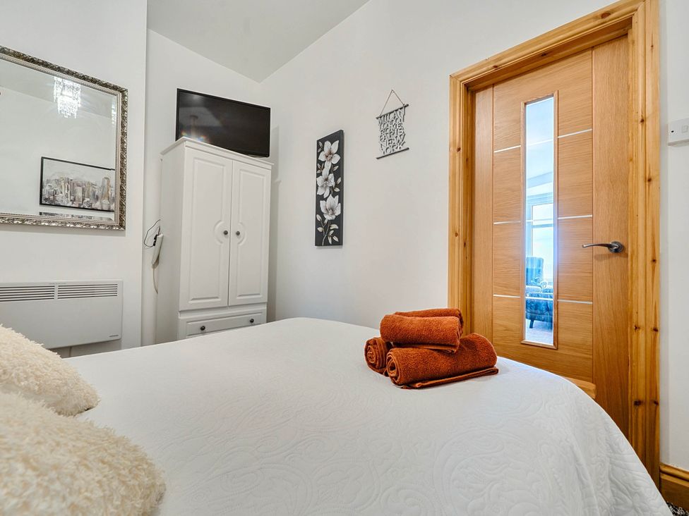 A bedroom with a bed, towels, and a TV at The Old Barn in Bispham