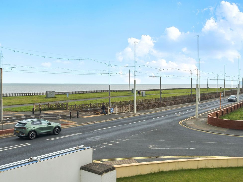 An outdoor view of a road with cars and a sea at a location in Bispham