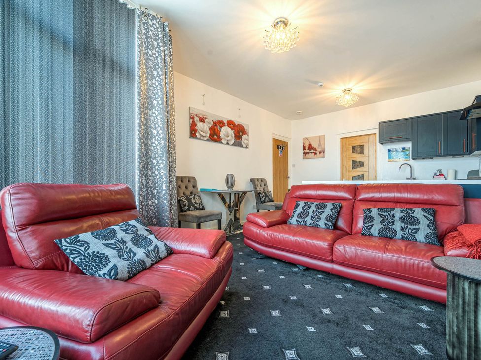 A living room with red sofas and a table at Ground Floor 1Bed Apartment at SeaCote Bispham