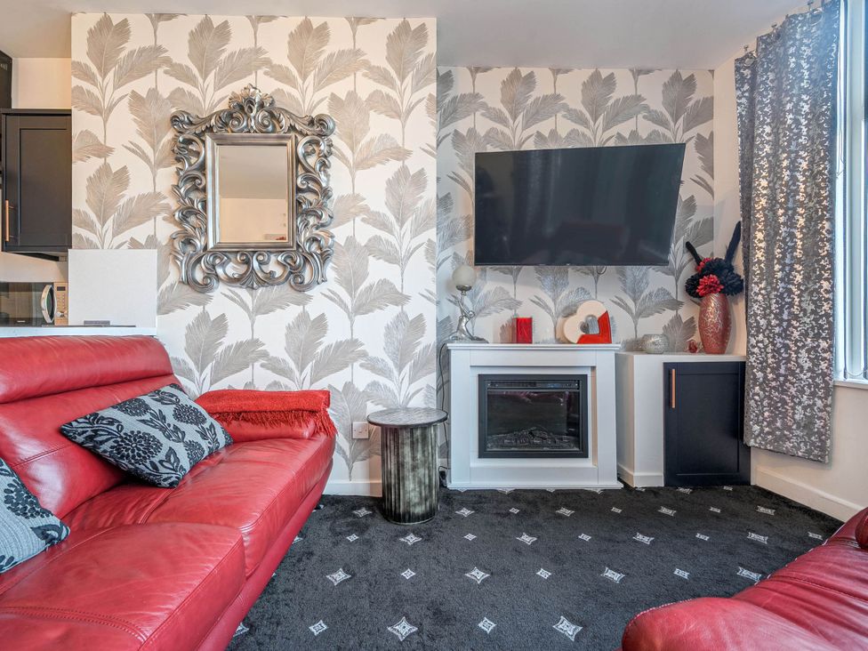 A living room with a red sofa and a television at Ground Floor 1Bed Apartment at SeaCote in Bispham