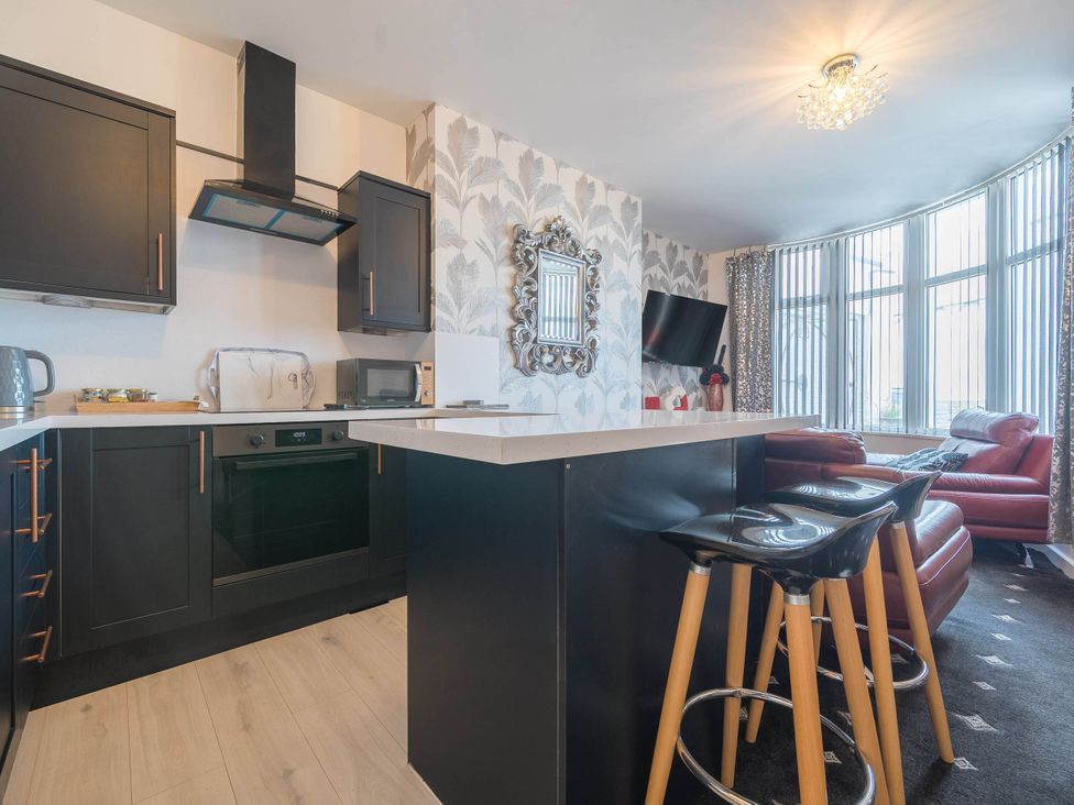 A kitchen with modern appliances and bar stools at Ground Floor 1Bed Apartment at SeaCote Bispham
