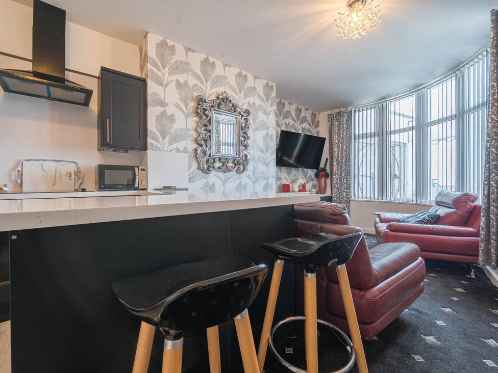 A living room with a kitchen countertop and bar stools at Ground Floor 1Bed Apartment at SeaCote Bispham