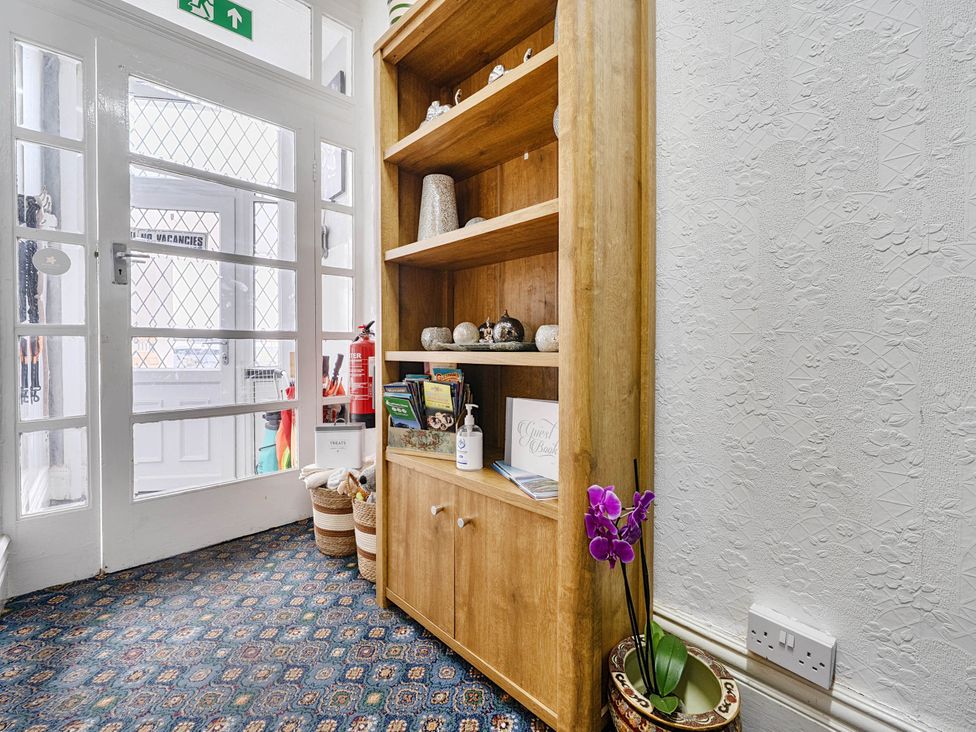 An entrance area with a wooden shelf and decorative items at Ground Floor Studio Apartment at SeaCote in Bispham