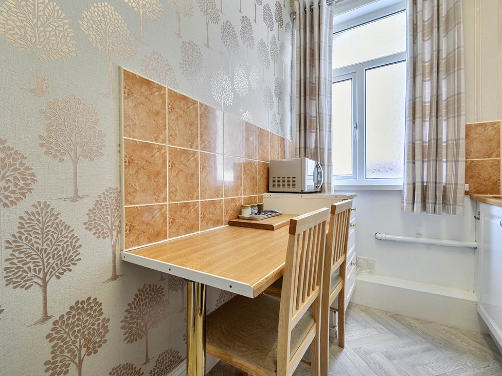 A kitchen area with a table and chairs at the Ground Floor Studio Apartment at SeaCote in Bispham
