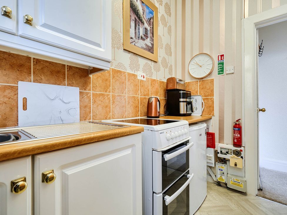 A kitchen with various appliances and a cutting board at Ground Floor Studio Apartment at SeaCote in Bispham