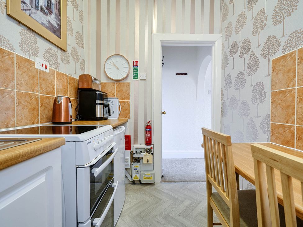 A kitchen with stove, kettle, microwave, and table at Ground Floor Studio Apartment at SeaCote in Bispham