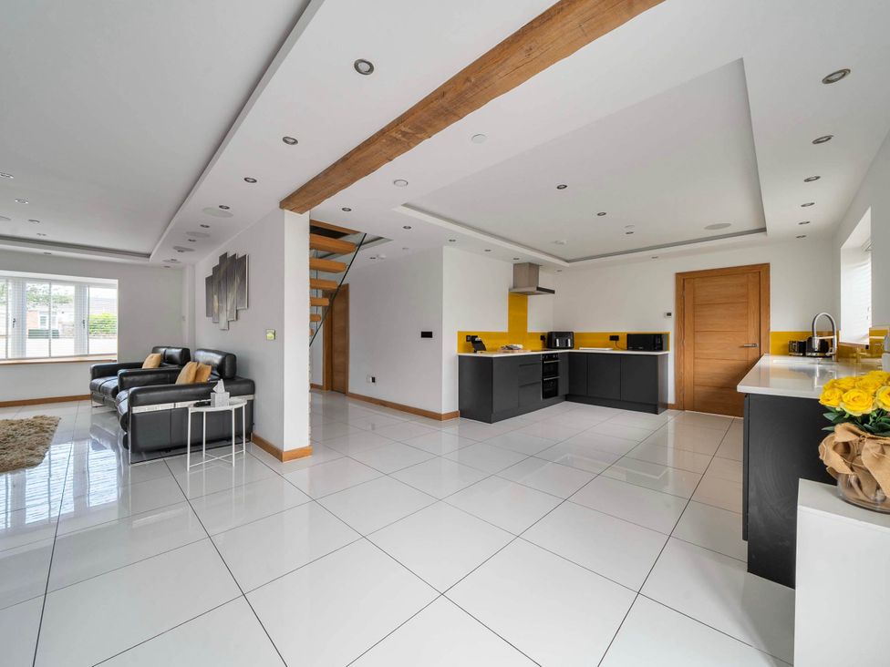 A living room with a sofa and kitchen area at The Old Barn in Abergele