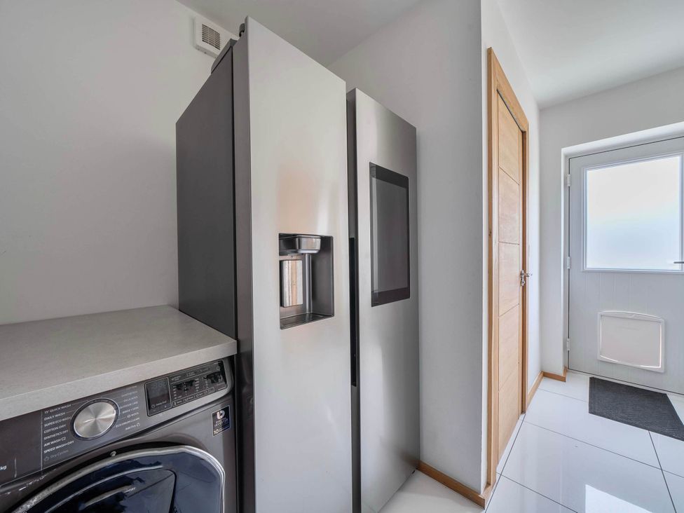 A laundry room with a refrigerator and washing machine at The Old Barn in Abergele