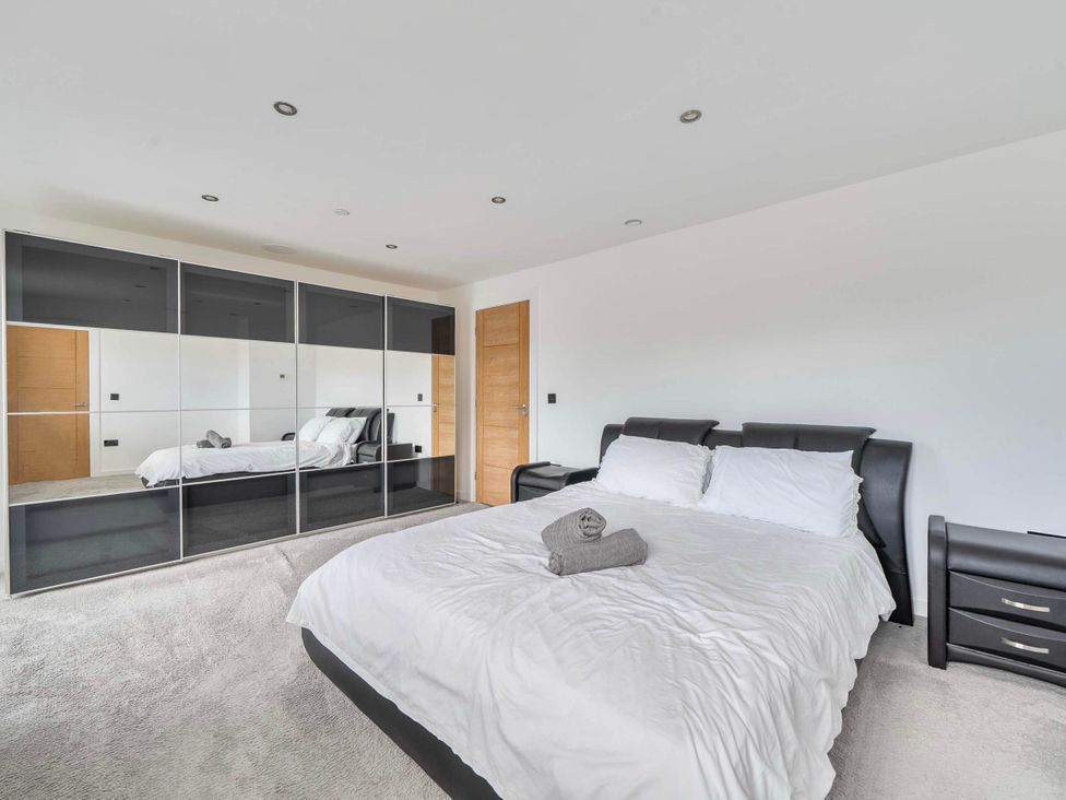 A bedroom with a bed and wardrobe at The Old Barn in Abergele