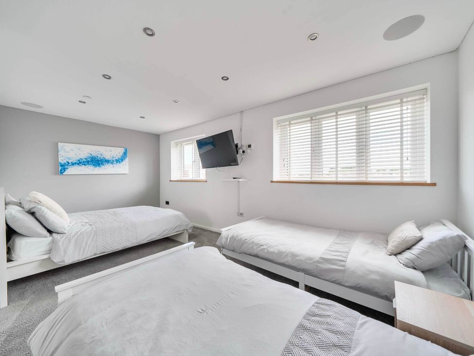 A bedroom with three beds and a TV mounted on the wall at The Old Barn in Abergele