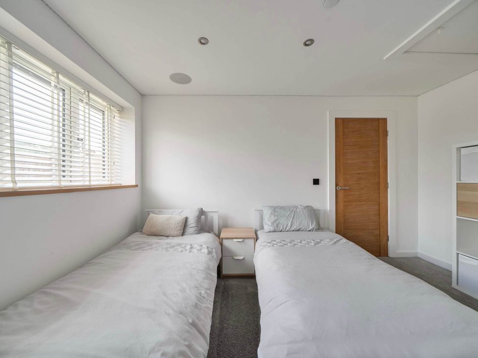 A bedroom with two beds and a nightstand at The Old Barn in Abergele