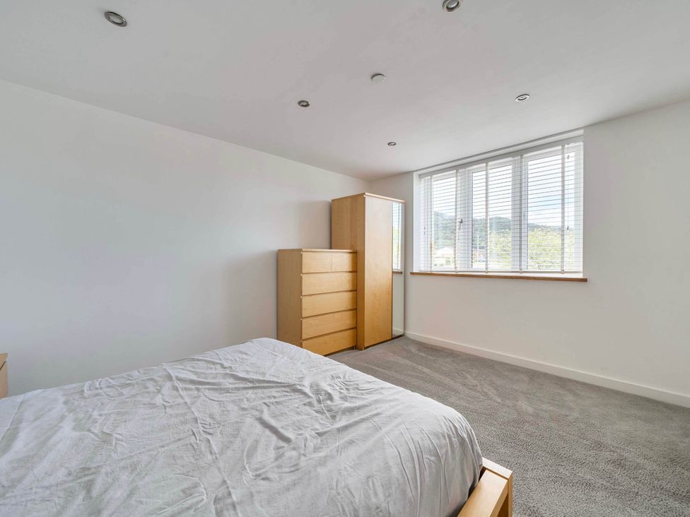 A bedroom with a bed and dresser at The Old Barn in Abergele