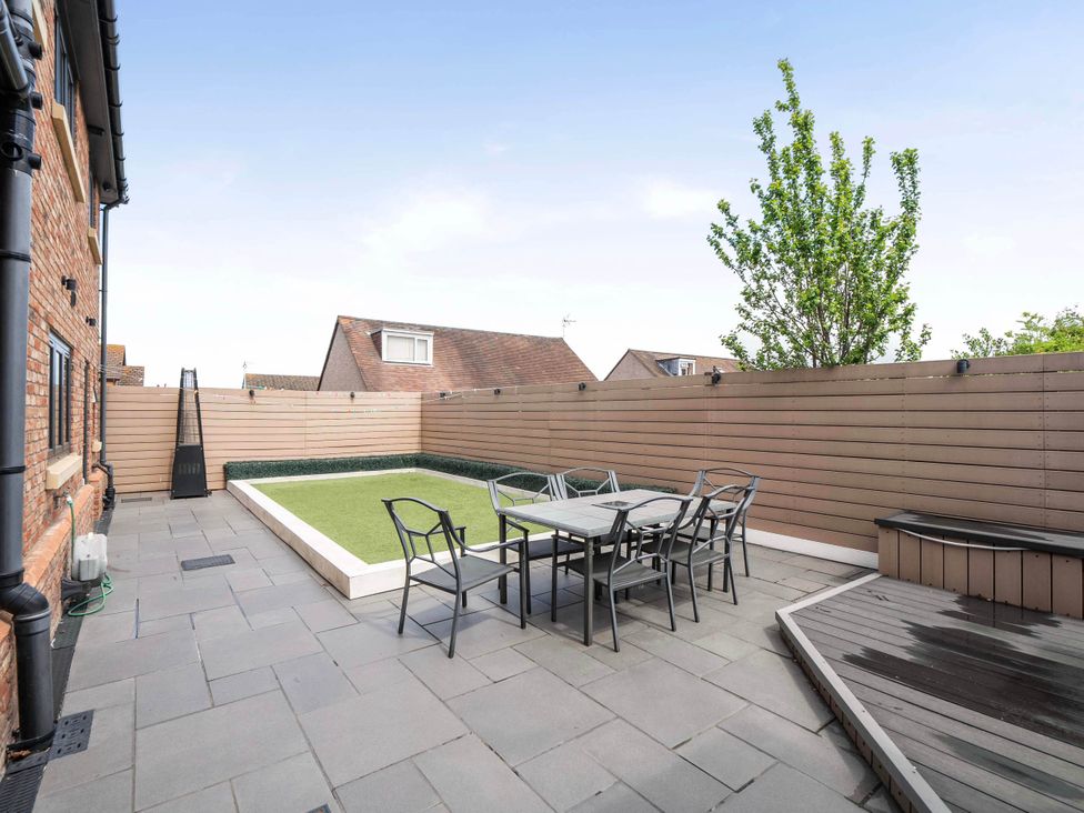 An outdoor patio with seating and a small lawn at The Old Barn in Abergele