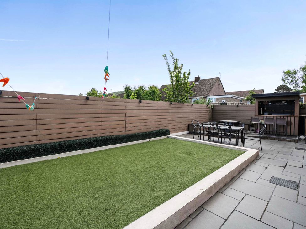 A garden with grass and patio seating at The Old Barn in Abergele
