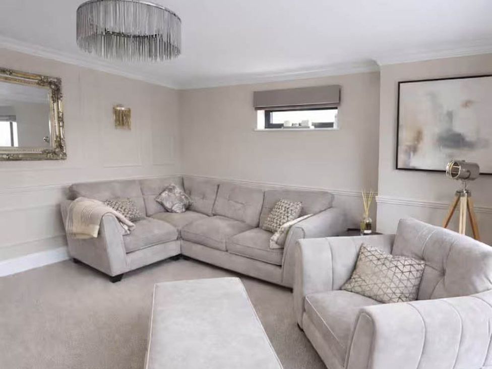 A living room with a sectional sofa and light fixture at Rochester Retreat Spacious 5 Bedroom House in Higham