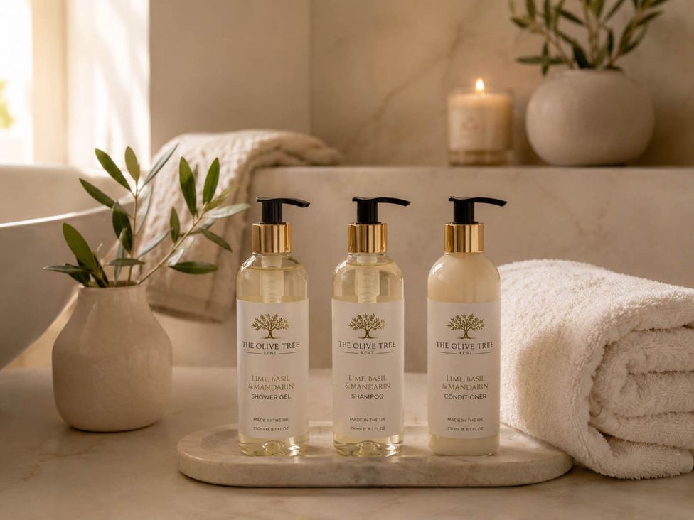 Bottles of shower gel, shampoo and conditioner on a tray with a towel at Rochester Retreat Spacious 5 Bedroom House in Higham