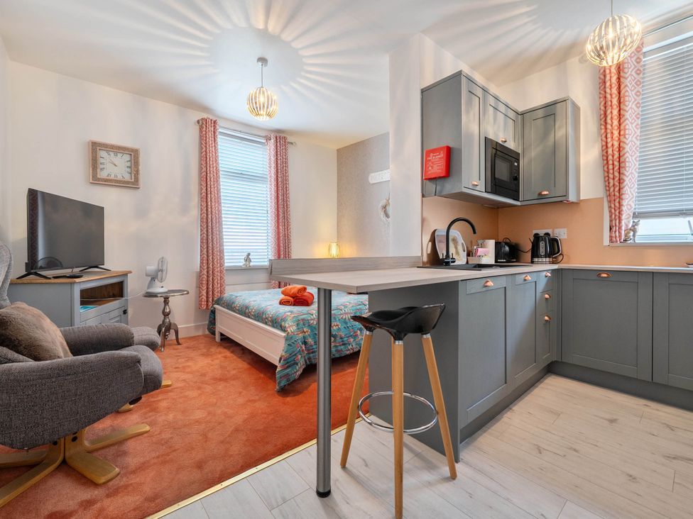 A studio apartment with a bed, kitchen area, and seating at The Old Barn in Manchester