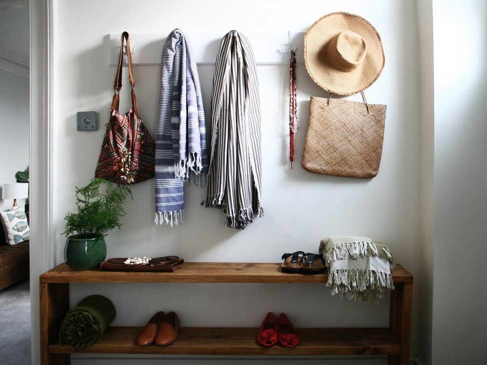 An entryway with coats and a hat on hooks and shoes on a bench at Beautiful 6Bed Sleeps 12 Stunning Views in Lynton