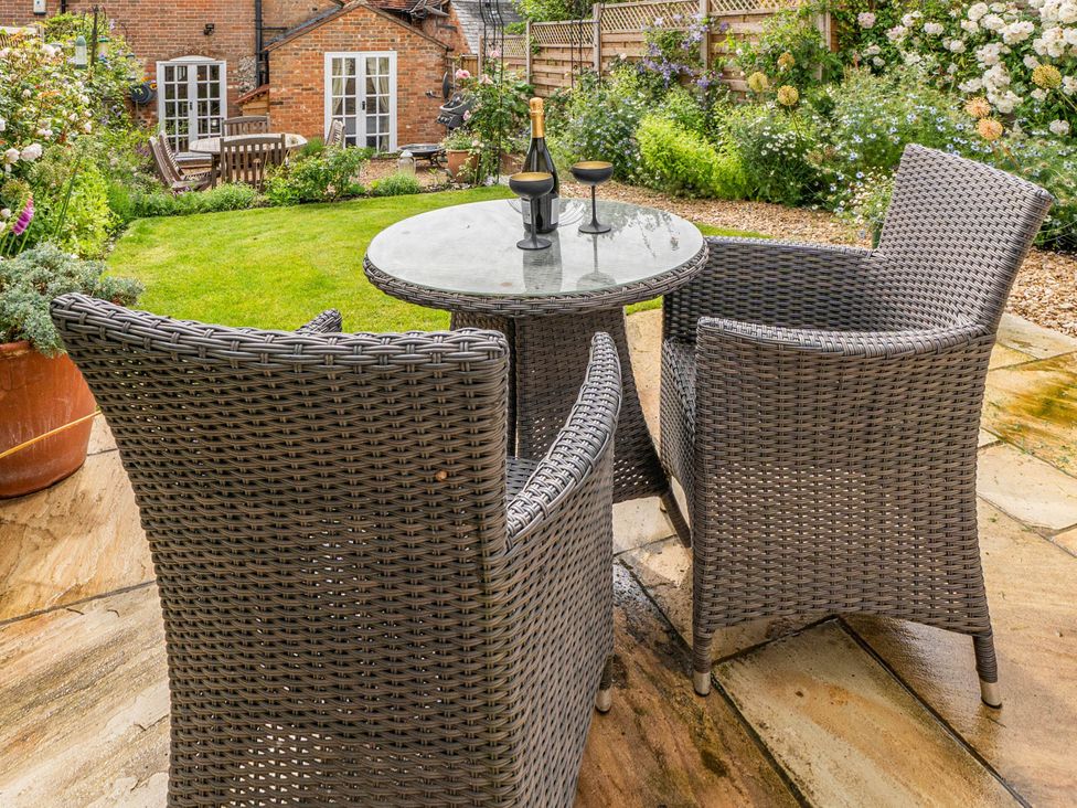 A garden with a table, chairs, and a bottle on top at Cottage Sleeps 4 with Enclosed Garden Turville near Henley-On-Thames