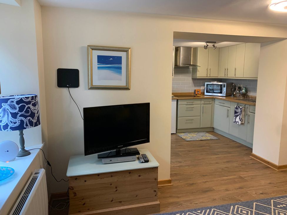 A living room with a television and kitchen area at 1 bed cottage Parking Patio close to coasts Coads Green near Launceston