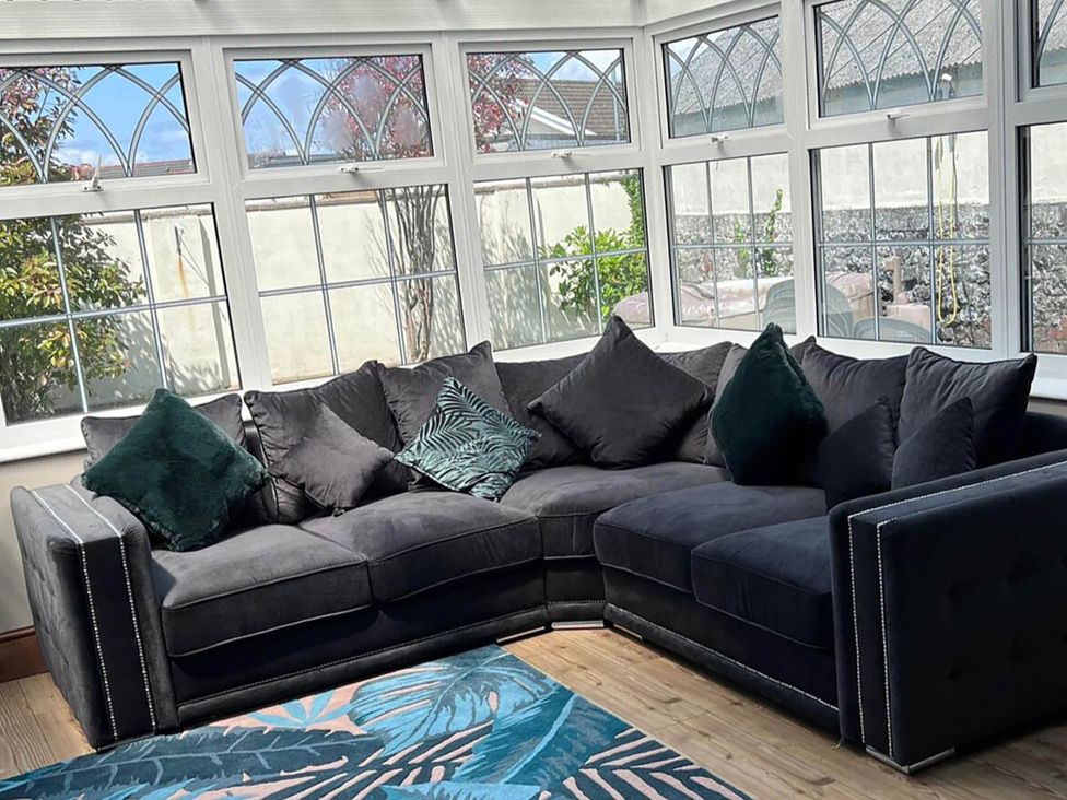 A conservatory with a sofa and windows at Build your memories hot tub garden sleeps 14 in Nottage