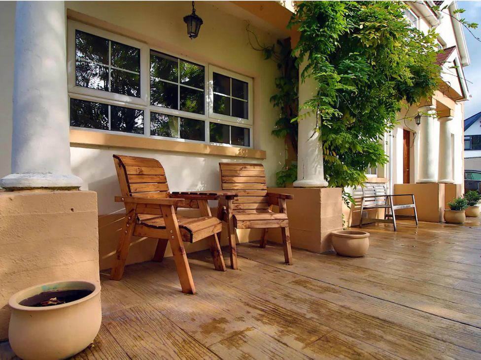 A outdoor seating area with wooden chairs and potted plants at Build your memories hot tub garden sleeps 14 Nottage