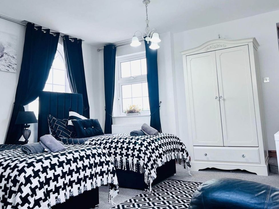 A bedroom with two beds and a wardrobe at Build your memories hot tub garden sleeps 14 in Nottage