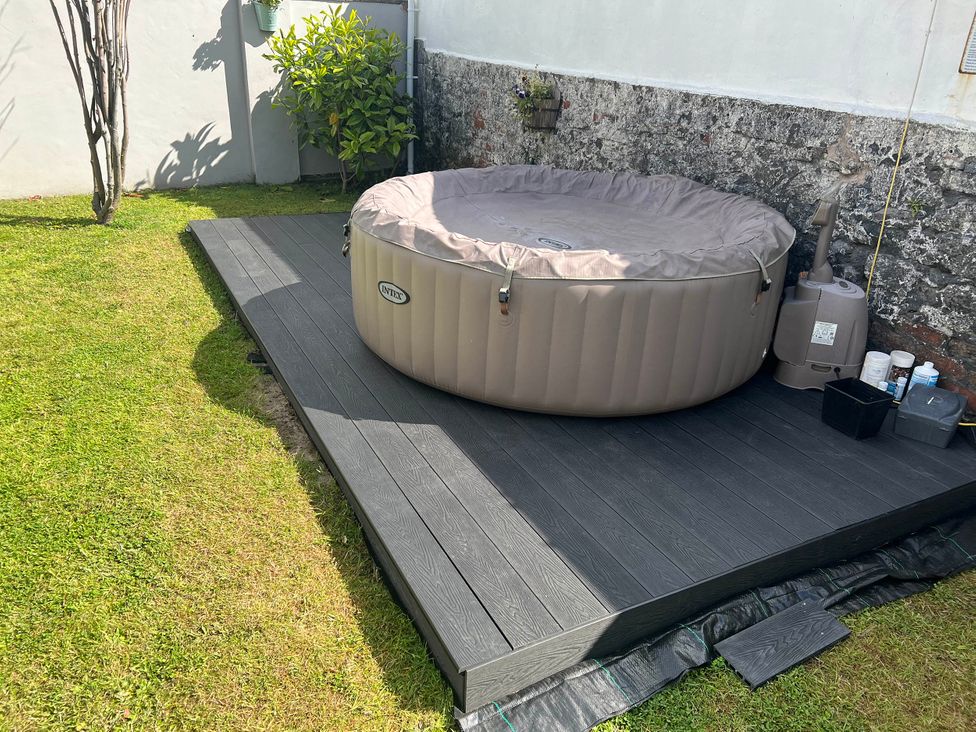 A hot tub with a plastic cover on decking in the garden at Build your memories hot tub garden sleeps 14 Nottage