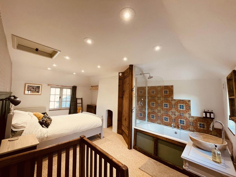A bedroom with an ensuite bathroom featuring a bathtub and shower at Charming Cottage Sleeps 4 with Sauna in Shaftesbury